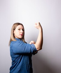 Vertical shot of a blonde caucasian female with a raised fist and rolled-up shirt