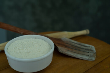A bowl of Flour and spoons beside it on a table, World Flour day and cooking concept Selective focus