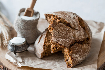 Fresh delicious bread close-up and salt. Freshly baked sourdough bread with a golden crust on a wooden board. The context of a bakery with delicious bread. Confectionery products.
