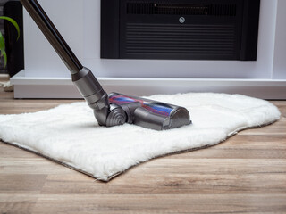 A woman vacuums the room with a modern vacuum cleaner. Cleaning of the apartment. Close-up.