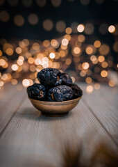 Dates fruits in a golden bowl with bokeh light background