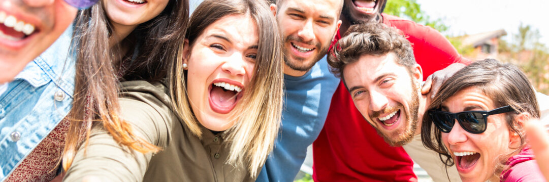 Group happy multiracial friends taking selfie in outdoors with mobile phone – diverse young people hugging selfie in outside with smartphone – horizontal web banner size for header 
