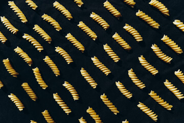 Macaroni fusilli on a black background, pattern