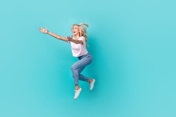 Fototapeta na wymiar Full length photo of satisfied adorable girl wear striped t-shirt running catch new clothes isolated on vivid turquoise color background