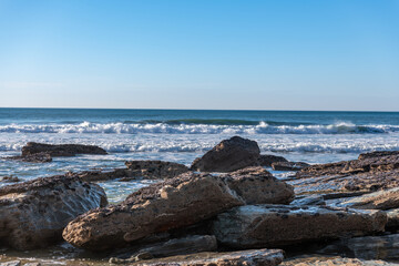 Trebarwith Strand Beach at low tide looking out to sea between rocks with waves breaking on the waters edge