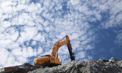 Naklejka premium Hydraulic breaker hammer excavator at demolition work. Excavator, digger taking down building. Demolition of an old building. Complete demolition work of the building with hydraulic shears. 