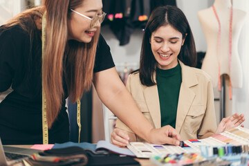 Fototapeta premium Happy beautiful Asia woman fashion designer clothes working with team in own dressmaking studio or boutique 