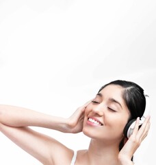 Beautiful Hispanic young woman listening to a music with headphones against a white background