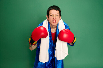 Portrait of aggressive boxer ready to punching and showing strength over green background. Concept...