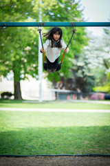 Young asian girl standing on a swing