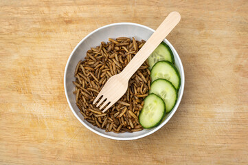 Mealworms with vegetable and wooden fork in a bowl, alternative protein rich diet