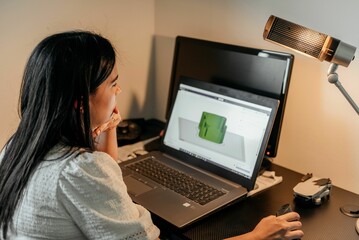 Female from behind sitting at her desk and working on her laptop