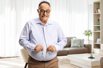 Mature man with a big belly trying to button a tight shirt