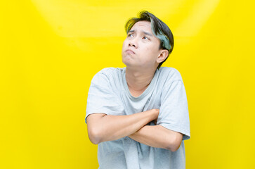 Thoughtful confused asian man thinking and wondering to choose something isolated over yellow background. indonesisan man feeling uncertain and unsure.	
