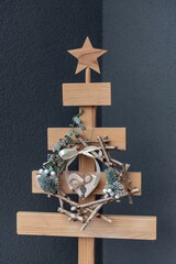 Wooden Christmas tree with decorations on a gray wall background