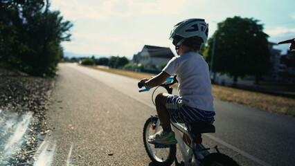 Kid learning to ride bicycle outside. Active little boy learning to ride bike with mother help and...