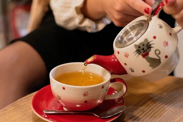 Closeup shot of a female pouring tea in a beautiful cup on an isolated background