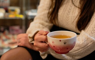 Closeup shot of a female holding a cup of tea in a sitting position on an isolated background