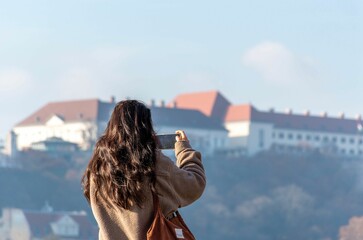 Fototapeta na wymiar Rear view of a female tourist taking photos of Buda castle in Budapest, Hungary