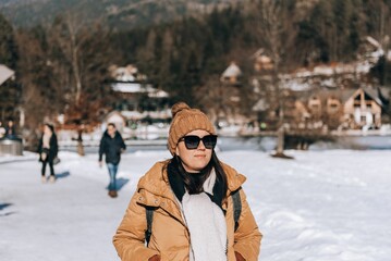 Fototapeta na wymiar Female tourist wearing winter clothes, walking on shore of Lake Jasna in Kranjska Gora, Slovenia