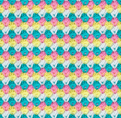 Seamless knitted texture in the form of flower buds. The pattern is crocheted from multi-colored acrylic yarn. Delicate range of shades.