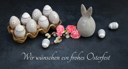 Osterkarte Frohe Ostern: Ostereier mit Blumen und einer Osterhasen Figur in einer Eierschachtel mit...