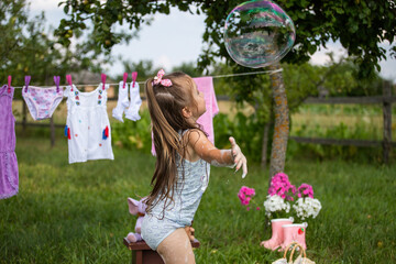 Fun kid fun. Washing in the fresh air. A child is playing in the garden. Little hostess. A little girl washes her clothes and plays with water. 