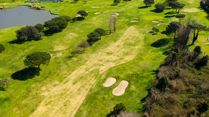 Aerial view of an empty golf course with green hills and sand bunkers. The sports club is empty and nobody is playing. Sports concept.