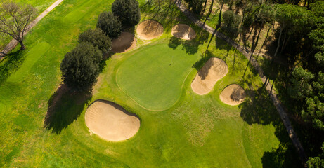 Aerial view of an empty golf course with green hills and sand bunkers. The sports club is empty and nobody is playing. Sports concept.