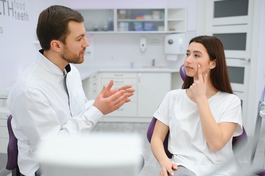 Image of pretty young woman sitting in dental chair at medical center while professional doctor fixing her teeth