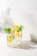 Refreshing drink with ice, lemon and mint. Cold lemonade on white background