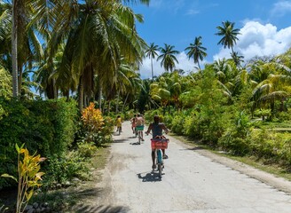 Local inhabitants riding bicycles on road on tropical island on a sunny day in summer