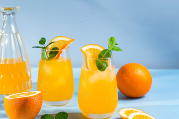 Fresh orange juice with ice in a glass on a blue background. orange cocktail