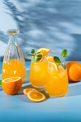 Fresh orange juice with ice in a glass on a blue background. orange cocktail