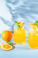 Fresh orange juice with ice in a glass on a blue background. orange cocktail