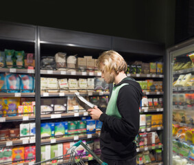 Man choosing frozen food from a supermarket freezer., reading product information