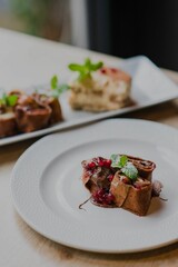 Vertical of two deserts on white plates on a wooden table against dark, blurred background