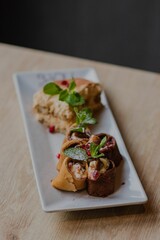 Vertical of two deserts on a white plate on a wooden table against dark, blurred background