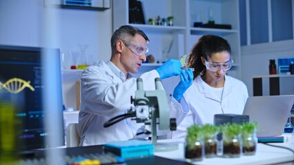 Two scientists studying mutation process of lab-grown plant, writing down data
