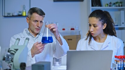 Chemistry scientist and student studying fluid sample in laboratory, internship