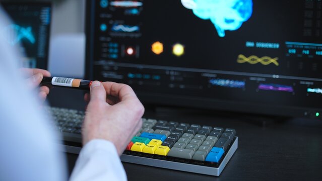 Medical lab scientist studying blood samples, typing in test results on computer