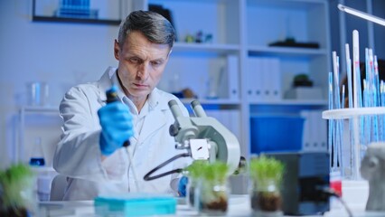 Agricultural laboratory scientist studying organic fertilizer under microscope