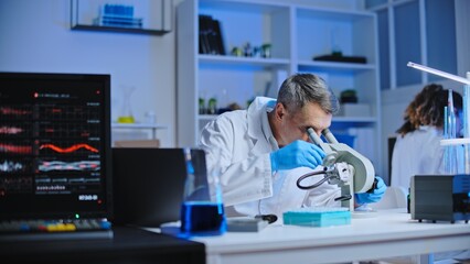 Laboratory scientist examining sample under microscope, conducting research