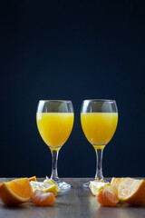 On the table are two glasses with an orange cocktail. Before them are oranges, lemons and tangerines. Copy space.