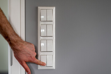 Row of eight light switches, while a finger switches on one light switch.