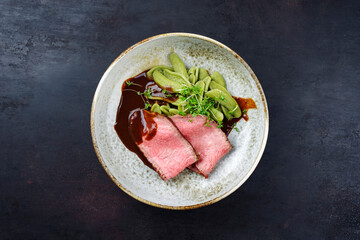 Traditionelles italienisches Chianina Roastbeef aufgeschnitten mit Spinat Nudeln in Rotwein Sauce serviert als Draufsicht in einer Nordic Design Schale mit Textfreiraum 