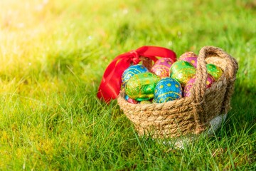 Easter eggs in basket in fresh green grass. Easter season banner with green nature bokeh background. Colorful decorated eggs in wicker basket. Spring season decoration for web banner