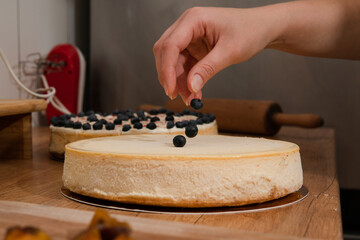 female hands decorate cake with berries