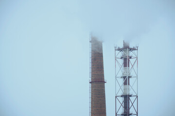 Two industrial pipes smoke polluting the environment with harmful gases.