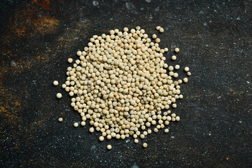White pepper peas. Spices and condiments. Top view. On a dark textured background.